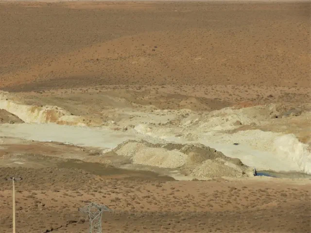 Pale excavated slopes and rock piles across a dry hillside
