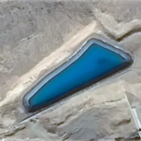 Satellite close-up of an elongated blue pool surrounded by bare ground