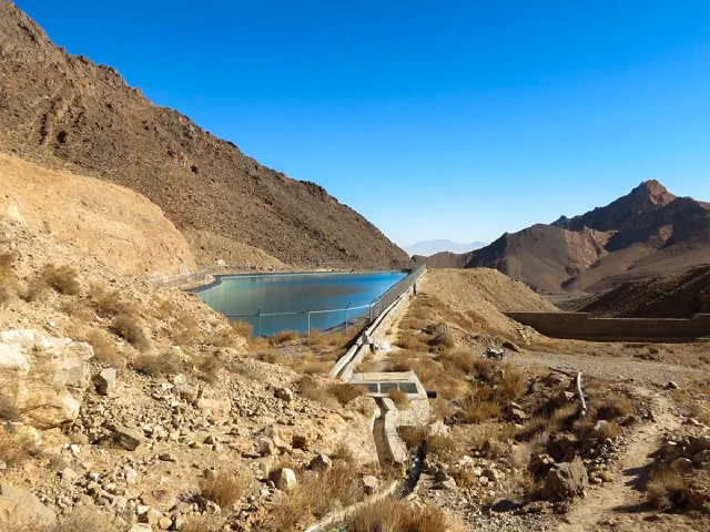 Water storage pool with a concrete edge between rocky mountain slopes