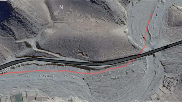 Satellite view of a dry channel marked in red beside a road