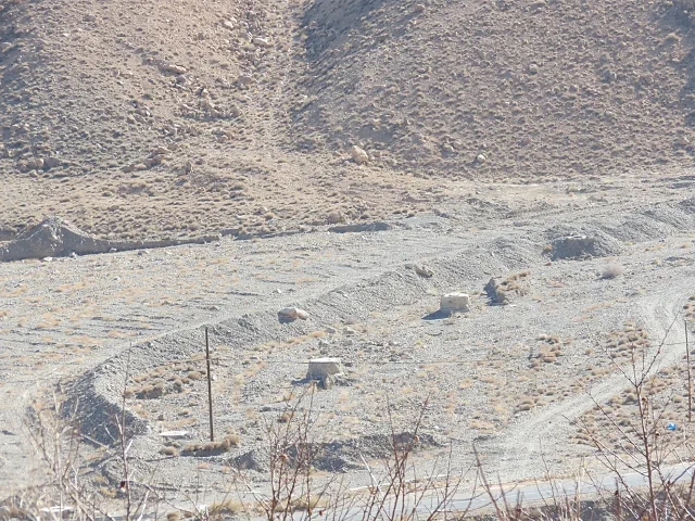 Small concrete structures spaced along a dry rocky channel