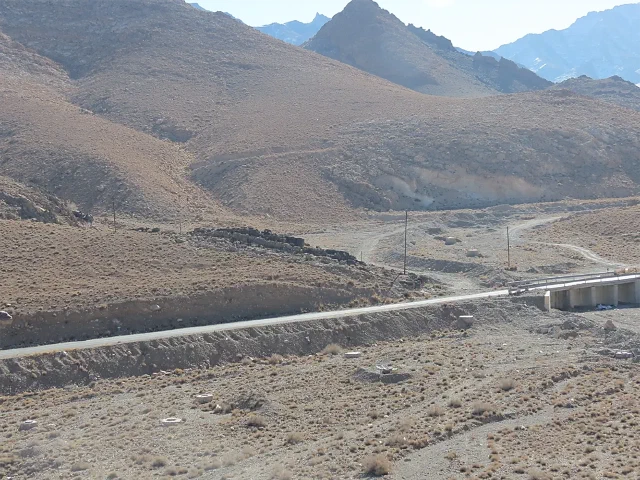 Dry valley with a long concrete wall and mountains in the background