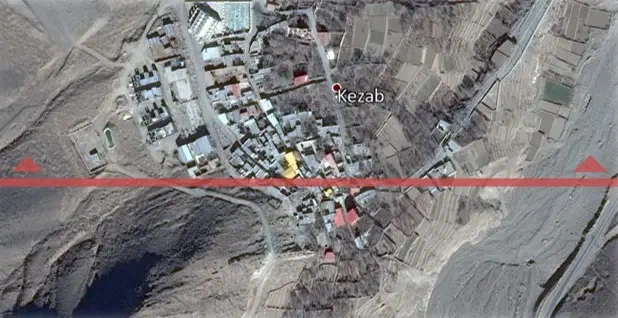 Satellite view of village buildings and fields crossed by a red section line