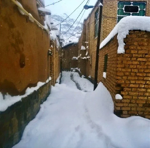 Narrow alley covered in snow between brick and earth-colored walls